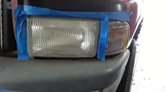 Headlight taped off around the lens for restoration