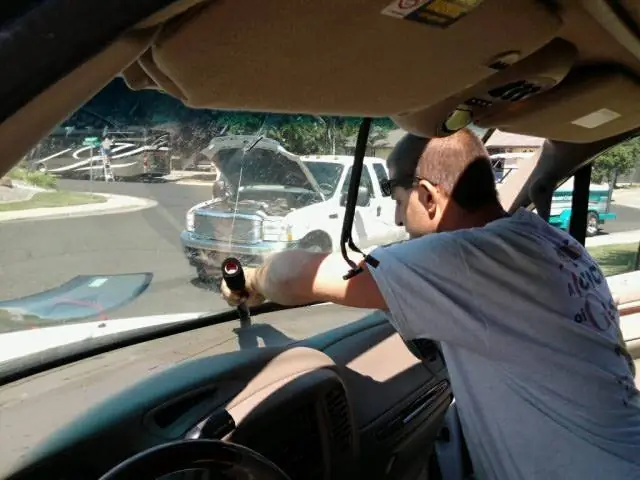 Installer working inside a vehicle cab on the door glass