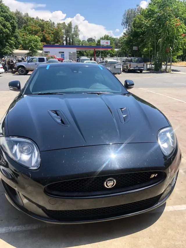 Front of a black Jaguar XK parked in the shop lot