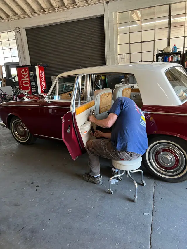 Installer working inside a vintage Rolls-Royce in the shop bay