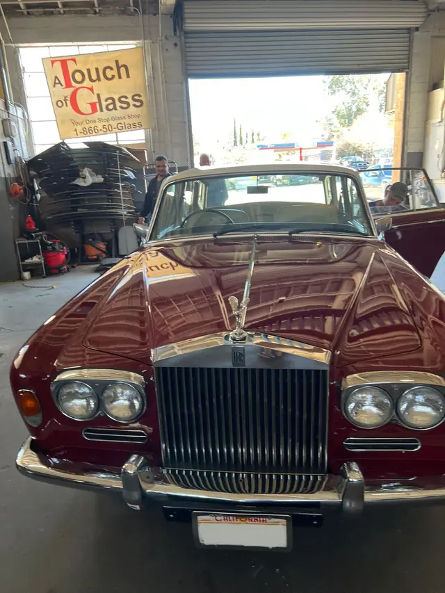 A vintage Rolls-Royce in the bay under the A Touch of Glass hanging sign